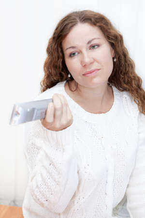 Girl with sour face changes channels television remote controlの写真素材