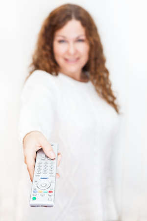 Girl with outstretched hand and a TV remote control on white backgroundの写真素材