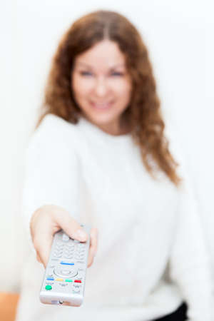 Young woman sitting with ctretched hands with tv remote control  Defocused の写真素材