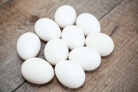 Ten chicken white eggs laying on wooden floor