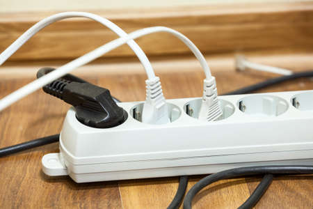 Many plugs plugged into electric power bar on office floor