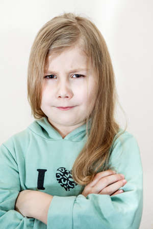 Young girl with an angry look and crossed arms. Head and shoulders portraitの写真素材