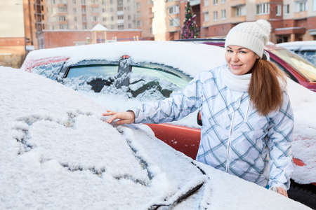 Beauty woman in the winter clothes with heart drawing on windshield of carの写真素材