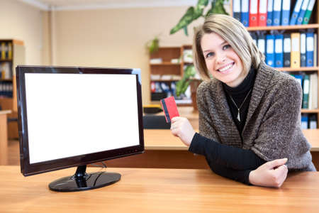 Office worker in front of a computer monitor with a credit card in handの写真素材