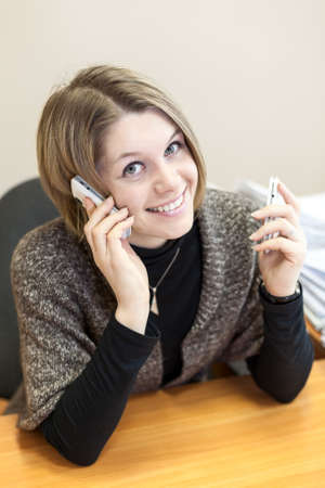 Pretty bland hair woman calling with two mobilesの写真素材