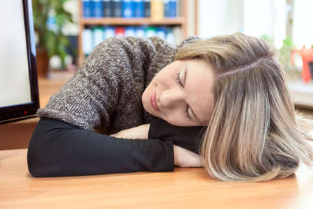 Attractive woman sleeping on hands at table in office