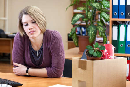 Dismissal - frustrated woman at a desk with a box with things