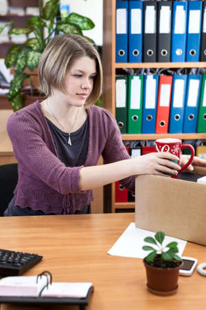 Woman collects things in a cardboard box in the workplaceの写真素材