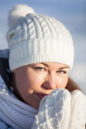 Facial portrait of woman in hat and mittens, heating handsの写真素材