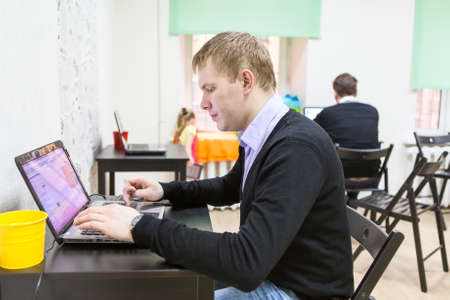 Young man sitting in room, typing on laptop computer