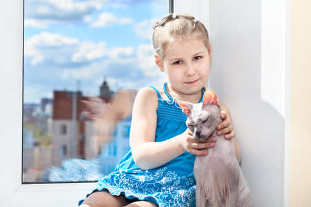 Young girl sitting with cat on window sillの写真素材