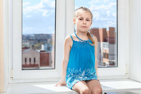 Young child sitting in middle of window sillの写真素材
