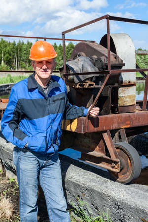 Senior worker standing near mechanism