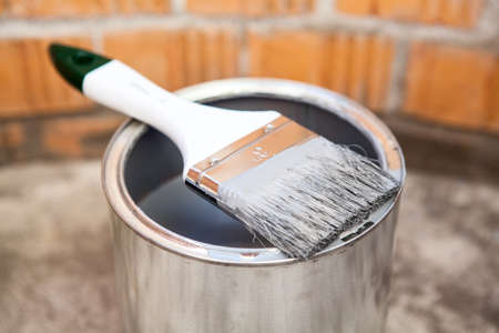 Paint brush in grey color laying on the canの写真素材