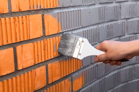 Human hand painting the wall with grey colorの写真素材