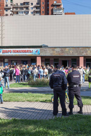SAINT-PETERSBURG, RUSSIA - CIRCA AUGUST, 2014: Police officers look at crowd of people in queue to buy swimming season ticket for kids. A small quantity of budgetary places for children in sports department.のeditorial素材