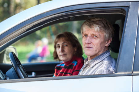 Senior Caucasian husband and wife sitting in land vehicle, looking through the windowの写真素材