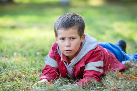 Pretty boy laying in grass at autumn seasonの写真素材