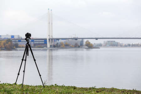 Camera for timelapse shooting on a professional tripod on the bridge background