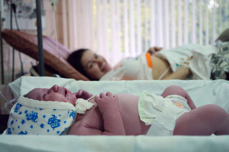 Newborn baby at desk next to her mother in the maternity hospitalの写真素材