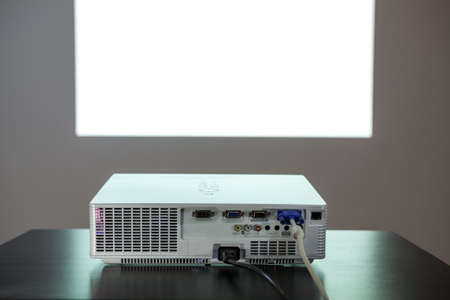 Digital media projector on the table, with middle size isolated white screen on the wall, nobodyの写真素材