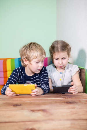 Small brother and sister using smartphones togetherの写真素材