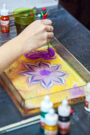 Painter working with basin for water surface marbling, drawing flowerの写真素材