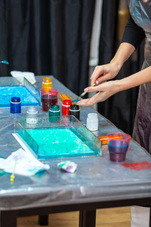 Woman starts to paint with dropping inks over blue water surfaceの写真素材