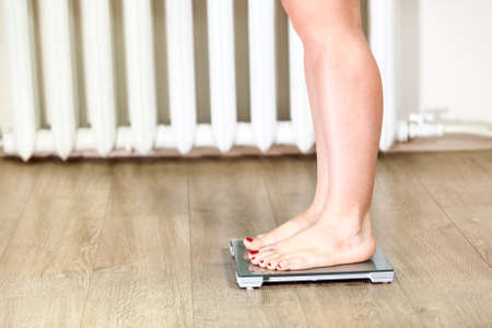 Female Caucasian legs standing on weight scaleの写真素材