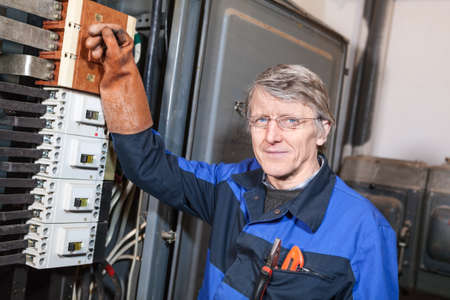 Electrical service worker turning on main switcher in high voltage boxの写真素材