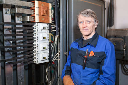 Mature electrician worker standing at work place and looking at camera