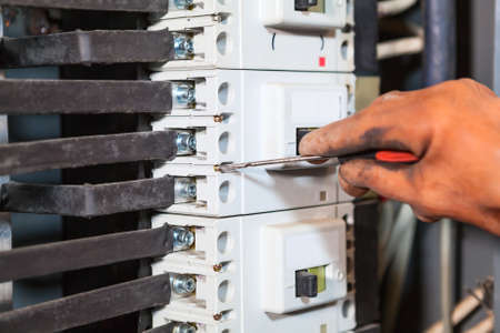 Electrician hand in rubber glove maintaining with screwdriver in high voltage boxの写真素材