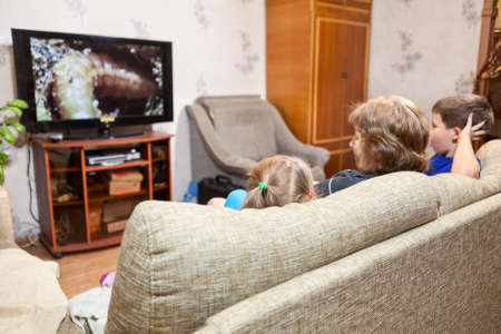 People watching tv at home, mother and her two kids a girl and boyの写真素材