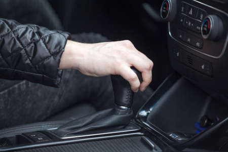 Caucasian female hand changing levels of automatic car gearbox, driver seat close up viewの写真素材