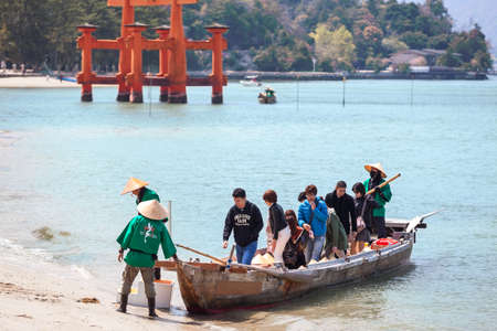 MIYAJIMA, JAPAN - CIRCA APR, 2013: Tourists come ashore from the boat after cruise under the torii...