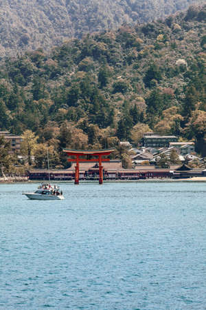 MIYAJIMA, JAPAN - CIRCA APR, 2013: Sacred Shinto red Torii and Itsukushima Shrine are on the shore of the island of Miyajima (Itsukushima) in Hiroshima gulf. View from the ferry-boatのeditorial素材