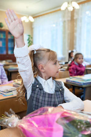 Small girl a student raising hand up for answer at school lessonの写真素材