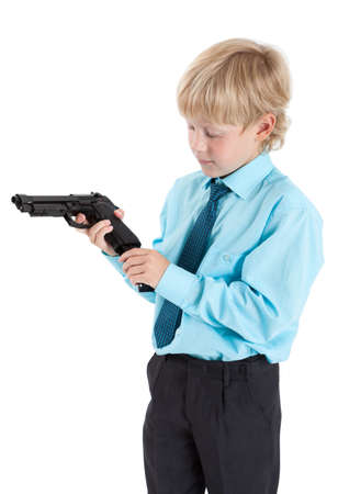 Caucasian boy in shirt with tie charging black gun in hands, isolated on white backgroundの写真素材