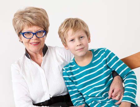 Caucasian elderly woman and young boy happy, portrait on a gray background