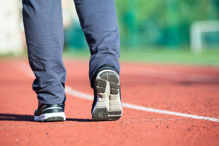 Close-up low angle rear view of sportsman legs wearing sports shoes, running lane of stadium, copyspaceの写真素材