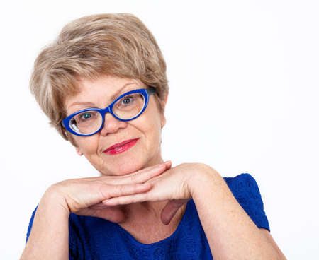 Senior Caucasian smiling woman propping head her hands and looking at camera, white backgroundの写真素材