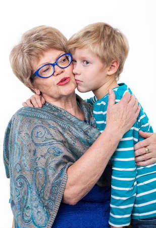 Kind grandmother calms down and embraces her sad grandson, on white backgroundの写真素材