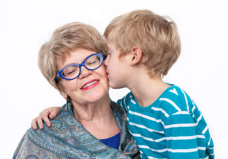 Grandson kissing happy grandmother on the cheek, white backgroundの写真素材
