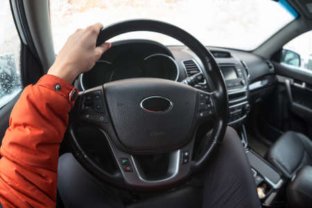 Male driver holding steering wheel with hand while sitting inside of car, wide angle view