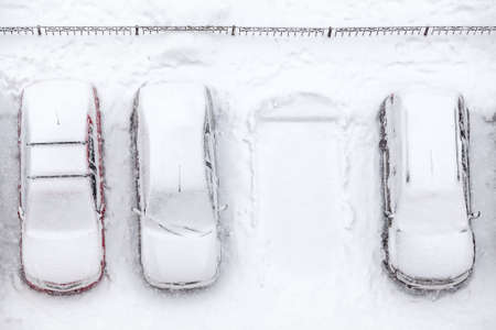 Covering with snow line of vehicles with vacant parking place, snowfall at winterの写真素材