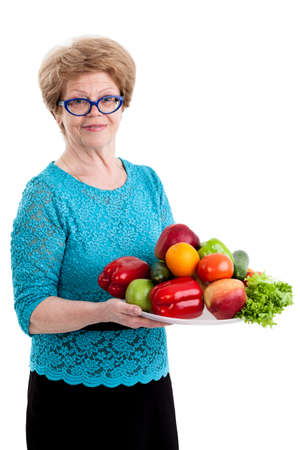 An elderly woman holding a tray with fruits and vegetables in hands, isolated white backgroundの写真素材