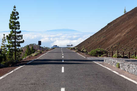 Mountain empty asphalt road going down in white clouds. Route in Teno massif, Tenerife, Canary islands, Spainの写真素材