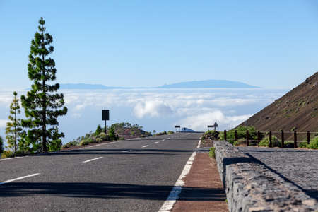 Mountain asphalt road road at sunny day. Clouds are below horizonの写真素材