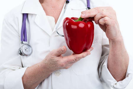 Large red bell pepper looks like heart is in the hands of doctor, isolated on white backgroundの写真素材
