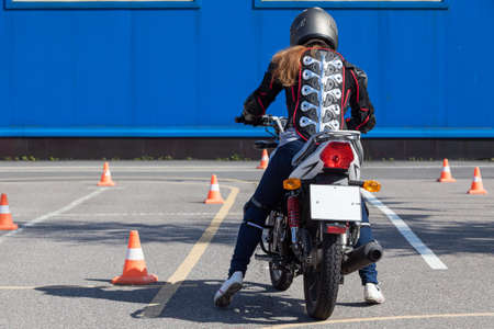 Woman motorcyclist has driving lesson on motordrome, rear viewの写真素材